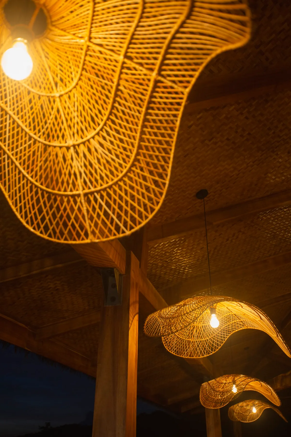 Woven rattan pendant lamps glowing over the dining pavilion at night